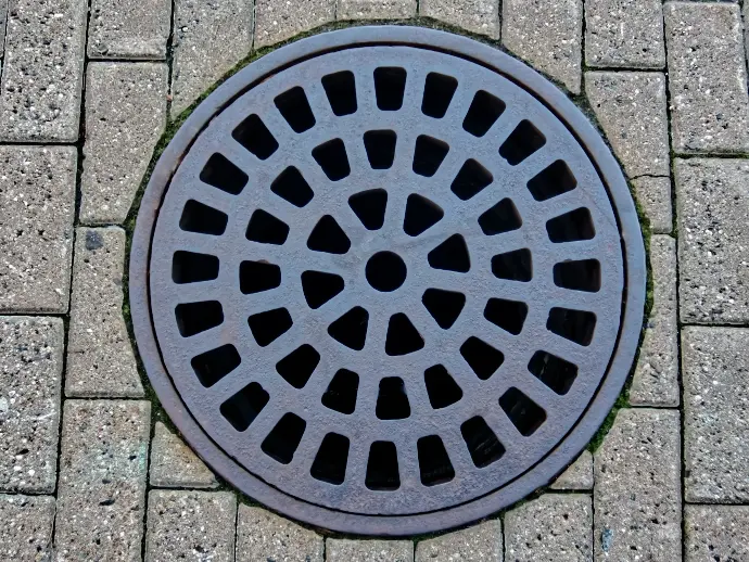 a manhole cover on a brick sidewalk